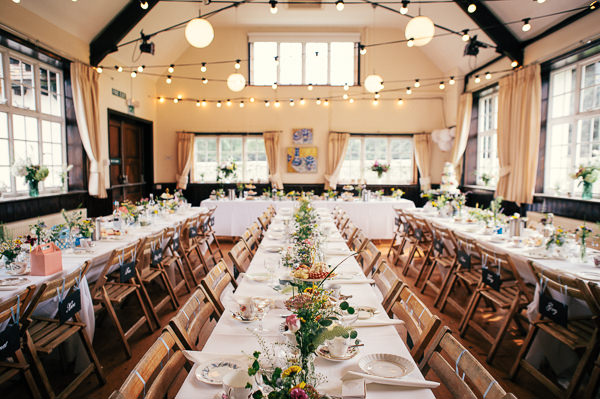 Colourful Homemade Village Hall Wedding Festoon Lights Long Tables http://hollydeacondesign.com/