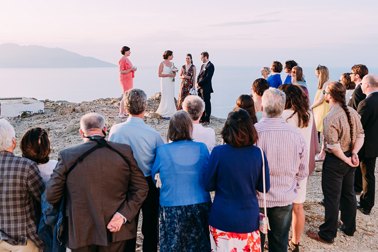 Outdoor Ceremony Bride Backless Bridal Gown Groom Navy Suit Blue Striped Tie Guests Ocean Breathtaking Intimate Mykonos Destination Wedding http://www.annapumerphotography.com/