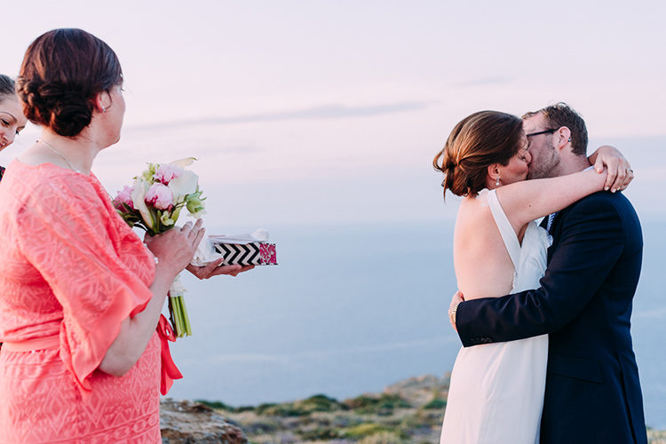 Outdoor Ceremony Bride Backless Bridal Gown Groom Navy Suit Kiss Pink White Lillies Bouquet Ring Box Breathtaking Intimate Mykonos Destination Wedding http://www.annapumerphotography.com/