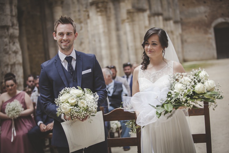Outdoor Ceremony Bride Lace Sleeveless Bridal Gown Loose Curls Veil Groom Navy Blue Suit Polka Dot Tie White Pocket Square Bouquet Cream Roses Gypsophila Bridesmaid Guests Atmospheric Abbey Tuscany Wedding http://www.angelicabraccini.com/