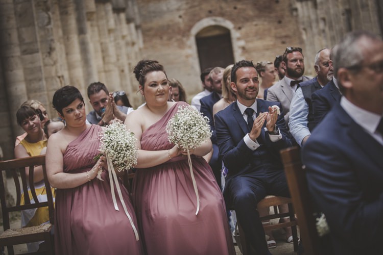 Outdoor Ceremony Bridesmaids Rose One Shoulder Dresses Bouquet Gypsophila White Ribbon Guests Wooden Chairs Atmospheric Abbey Tuscany Wedding http://www.angelicabraccini.com/