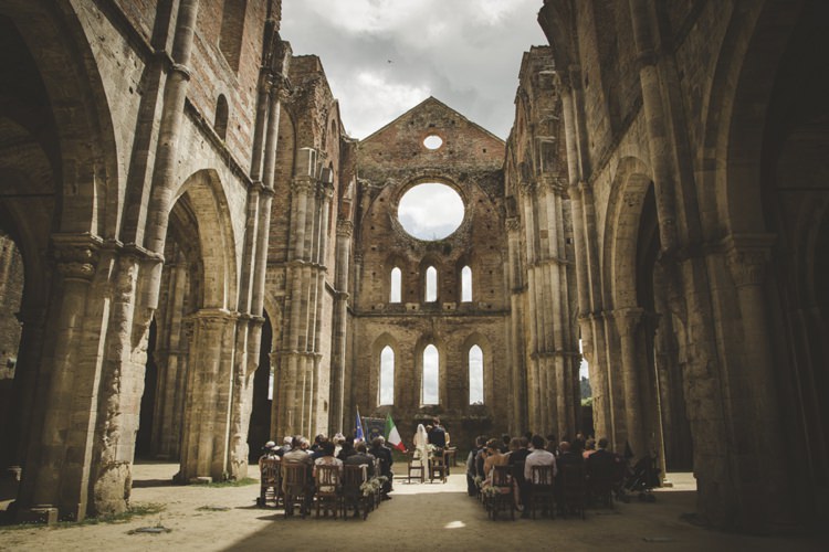 Outdoor Ceremony Guests Bride Groom Flags Cloudy Skies Atmospheric Abbey Tuscany Wedding http://www.angelicabraccini.com/