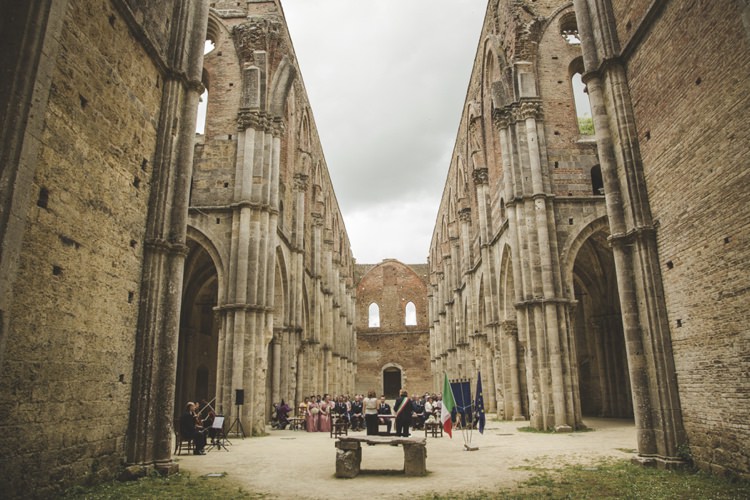 Outdoor Ceremony Guests Flags String Music Cloudy Skies Atmospheric Abbey Tuscany Wedding http://www.angelicabraccini.com/