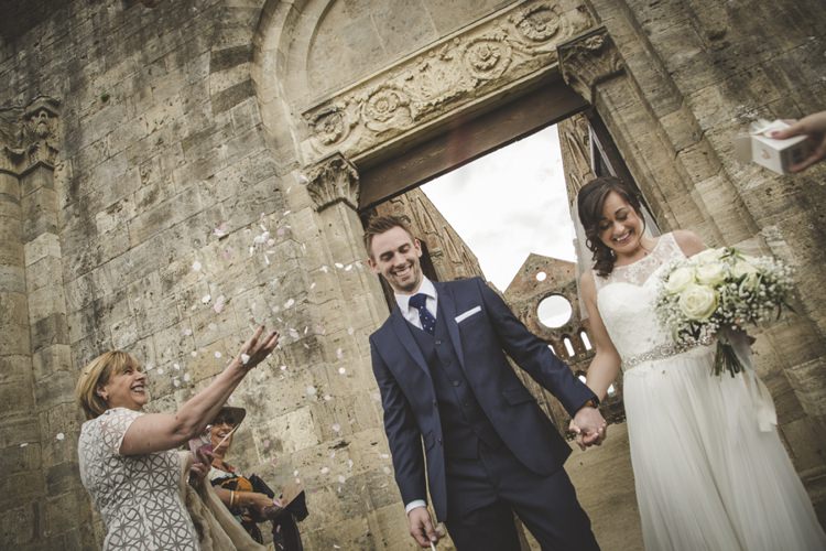 Outdoor Ceremony Bride Lace Sleeveless Bridal Gown Beaded Belt Loose Curls Veil Bouquet Cream Roses Gypsophila Groom Navy Blue Suit Polka Dot Tie White Pocket Square Guests Flower Petals Atmospheric Abbey Tuscany Wedding http://www.angelicabraccini.com/