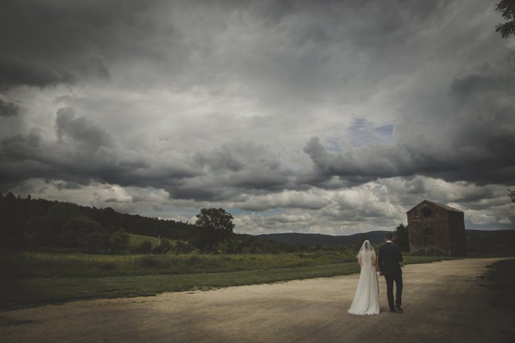 Bride Lace Sleeveless Bridal Gown Veil Groom Navy Blue Suit Dark Cloudy Skies Green Hillside Dirt Road Atmospheric Abbey Tuscany Wedding http://www.angelicabraccini.com/