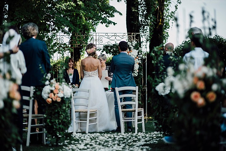 Ceremony Bride Lace Halter-Neck Top Tulle Skirt Floral Hairstyle Groom Grey Suit Vintage Archway White Peach Florals Hydrangea Roses White Chairs Petals Outdoor Floral Countryside Wedding Veneto http://serenagenovese.com/