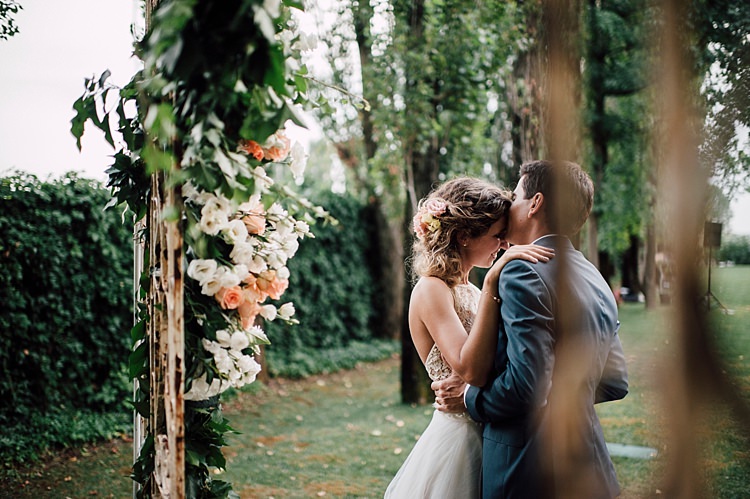 Bride Lace Halter-Neck Top Tulle Skirt Floral Hairstyle Groom Grey Suit Vintage Archway White Peach Flowers Roses Peonies Hydrangea Greenery Outdoor Floral Countryside Wedding Veneto http://serenagenovese.com/