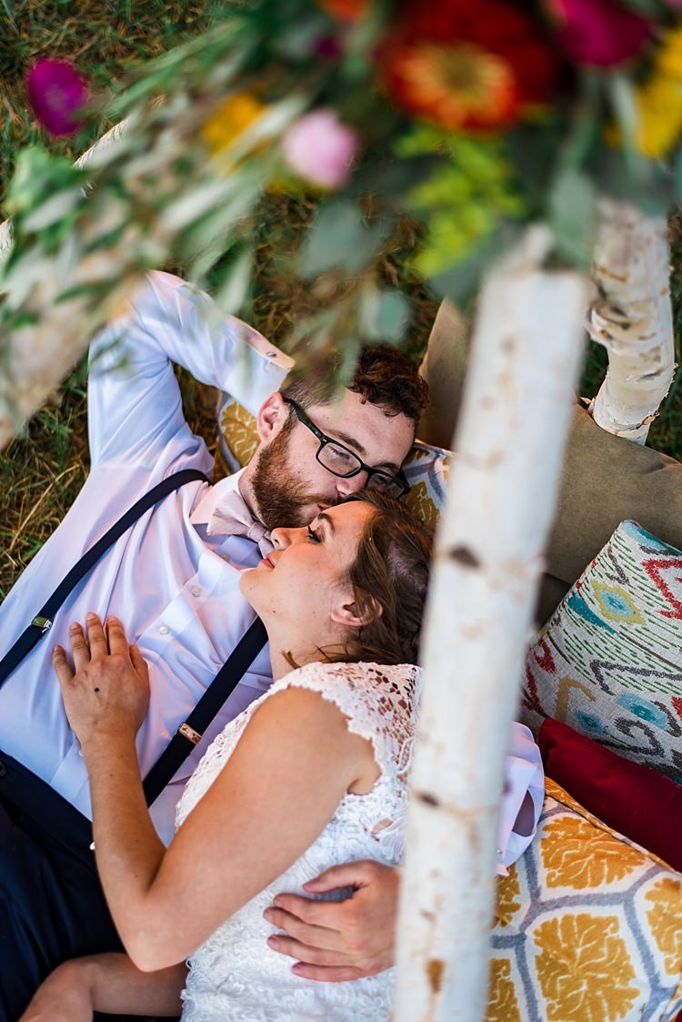 Bride Lace Bridal Gown With Buttons Groom Navy Pants Suspenders Cream Bow Tie Teepee Multicoloured Florals Pink Yellow Red Orange Patterned Cushions Grass Ethereal Boho Wedding Ideas http://perfectcapturephoto.com/