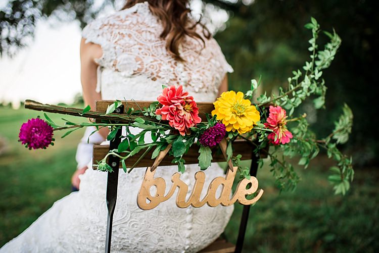 Bride Lace Bridal Gown With Buttons Wooden Chair Multicoloured Floral Decoration Gold Metallic Bride Sign Ethereal Boho Wedding Ideas http://perfectcapturephoto.com/