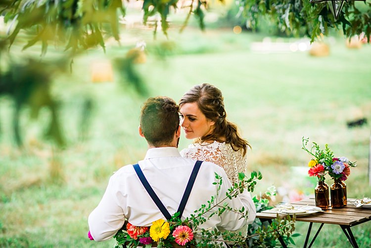 Bride Lace Bridal Gown With Buttons Groom Navy Suspenders Wooden Table Colourful Flowers Brown Glass Vases Chair Multicoloured Floral Decoration Trees Grass Ethereal Boho Wedding Ideas http://perfectcapturephoto.com/