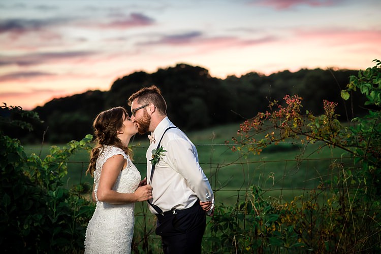 Bride Lace Bridal Gown With Buttons Groom Navy Pants Suspenders Cream Bow Tie Buttonhole Sunset Grass Trees Kiss Ethereal Boho Wedding Ideas http://perfectcapturephoto.com/
