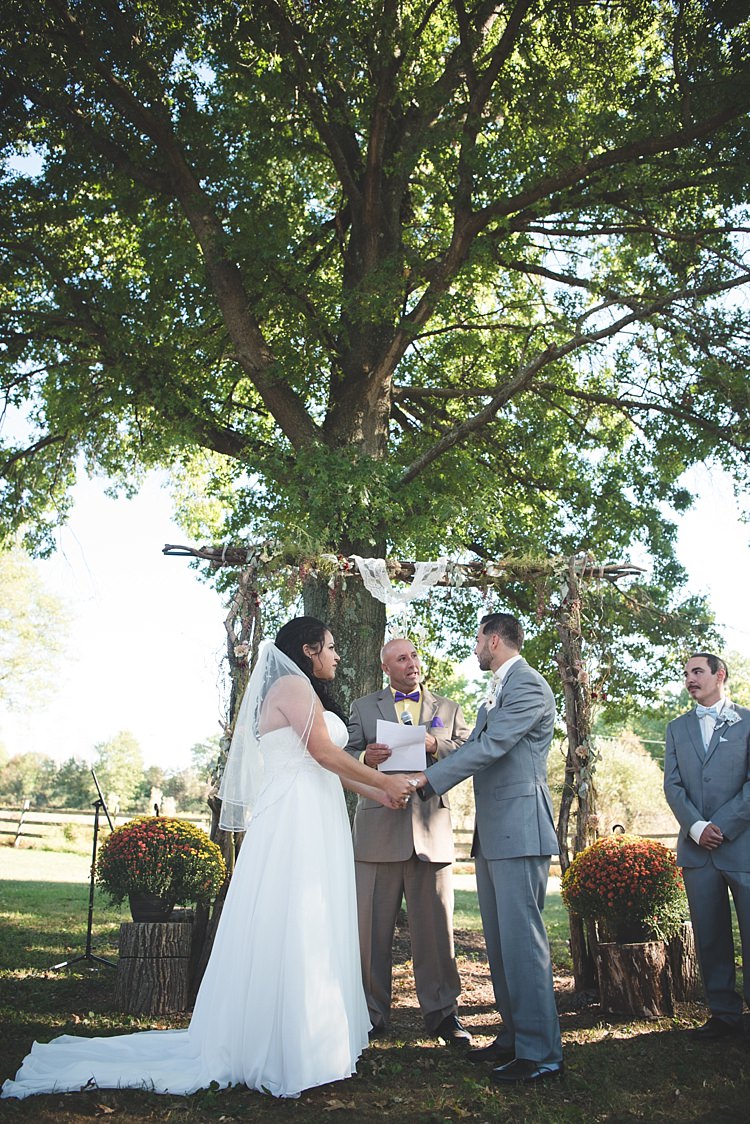 Outdoor Ceremony Decorated Arch Bride Strapless Gown With Train Veil Groom Grey Suit White Bowtie Celebrant Leafy Tree Potted Flowers Alice in Wonderland Wedding Pennsylvania http://www.julieflorophotography.com/