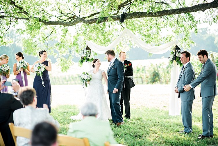 Outdoor Ceremony Bride Lace Cap Sleeve Bridal Gown Bouquet Groom Navy Suit Purple Tie Bridesmaids Groomsmen Hanging Décor Outdoor Spring Vineyard Wedding Tennessee http://www.juicebeatsphotography.com/