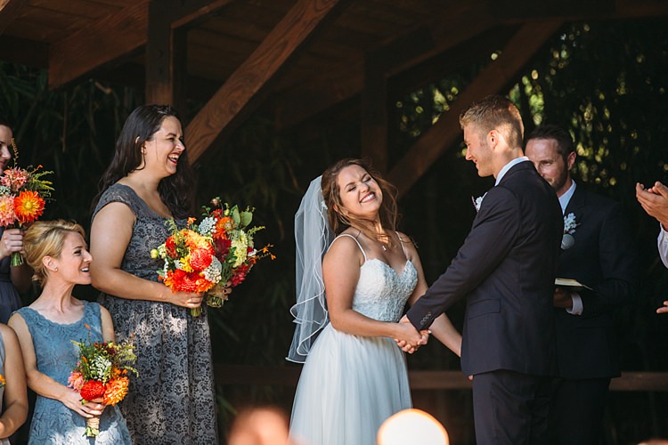 Outdoor Ceremony Bride Lace Tulle Bridal Gown Grey Sash Veil Groom Navy Blue Suit Grey Tie Floral Button Hole Bridesmaids Grey Blue Dresses Bright Orange Red Yellow Bouquets Organic Farm Wedding Washington http://www.katiedayphotos.com/