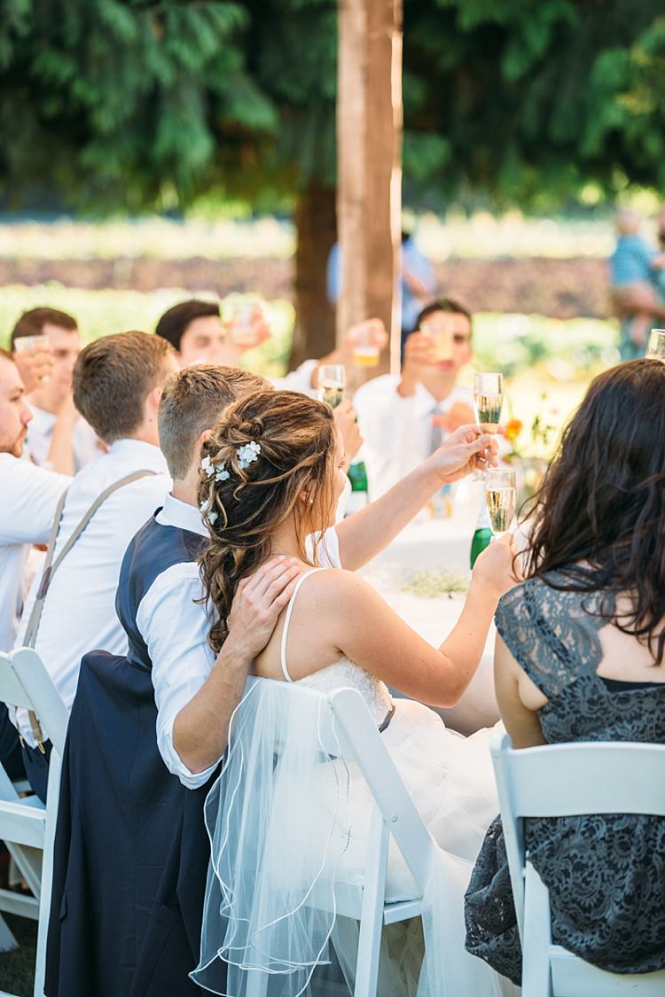 Outdoor Reception Bride Lace Tulle Bridal Gown Grey Sash Loose Curls Hairstyle Flowers Groom Navy Blue Vest White Shirt Guests Cheers Organic Farm Wedding Washington http://www.katiedayphotos.com/