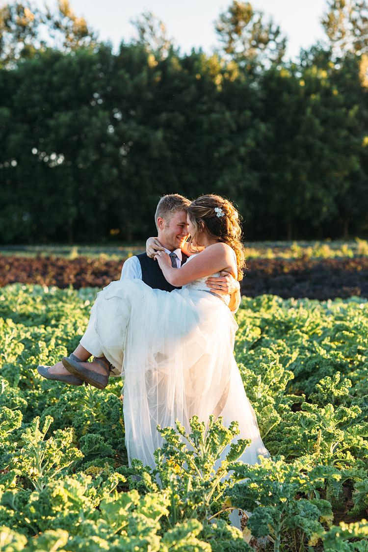 Bride Lace Tulle Bridal Gown Grey Sash Loose Curls Hairstyle Flowers Tattoo Grey Flat Shoes Groom Navy Blue Suit Vest Grey Tie Vegetable Patch Sunset Organic Farm Wedding Washington http://www.katiedayphotos.com/
