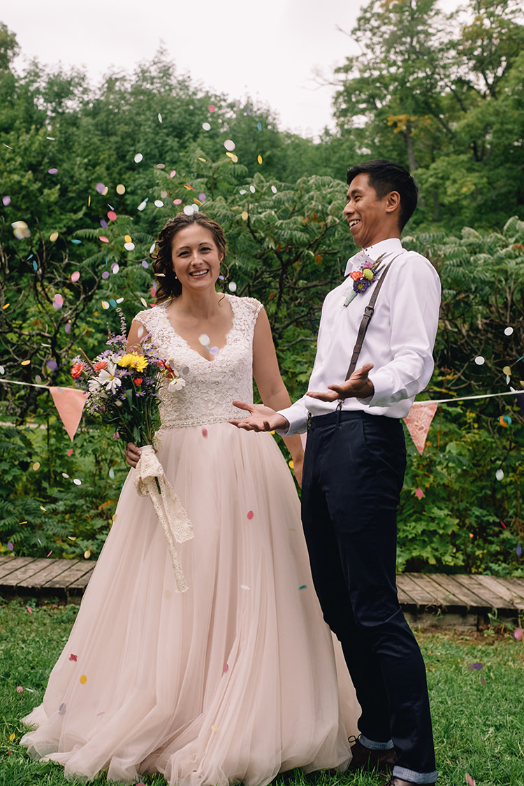 Bright Confetti Bride Allure Champagne Lace Tulle Bridal Gown Multicoloured Floral Bouquet Lace Ribbon Groom White Shirt Brown Leather Suspenders Navy Pants Multicoloured Floral Buttonhole Bunting Woodland Waterfall Mint Wedding Ontario http://www.laurenmccormickphotography.com/