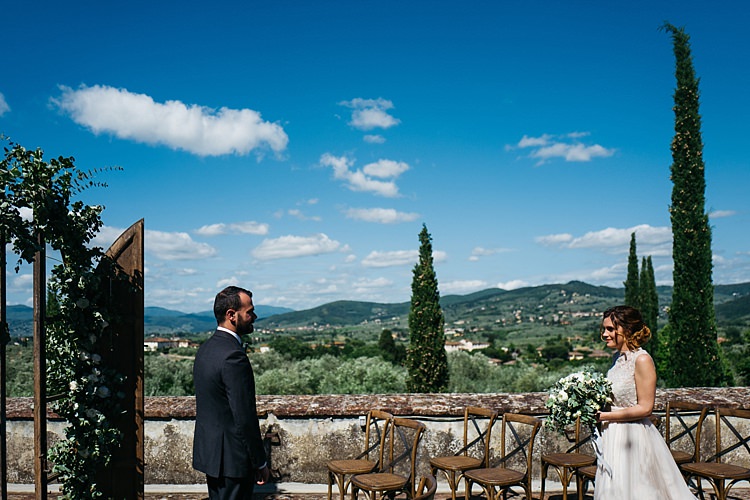 Outdoor Ceremony Bride High Neck Lace Tulle Bridal Gown Bouquet Groom Charcoal Pinstripe Suit Wooden Archway Greenery White Florals Wooden Chairs Beautiful Views Rustic Chic Greenery Wedding Ideas in Tuscany http://www.tastino0.it/