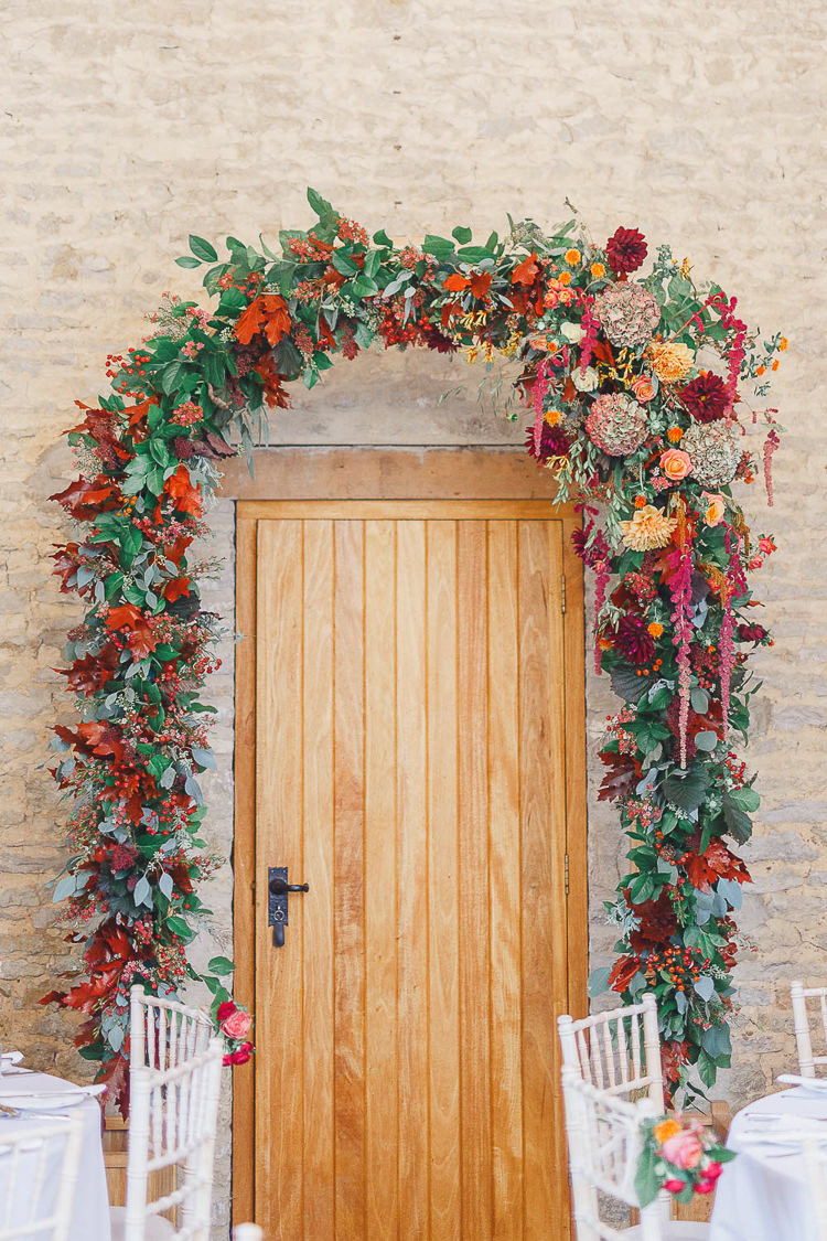Arch Flowers Red Orange Dahlia Rose Arrangement Foliage Doorway Berry Magical Fairy Lit Autumn Barn Wedding http://whitestagweddings.com/