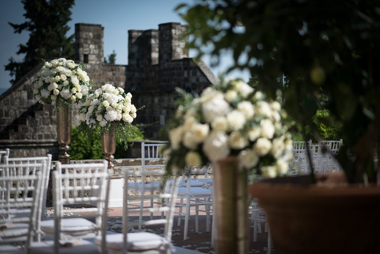Outdoor Ceremony Metallic Pillars White Roses White Chairs Potted Plants Romantic Outdoor Castle Tuscany Wedding http://www.natalymontanari.com/