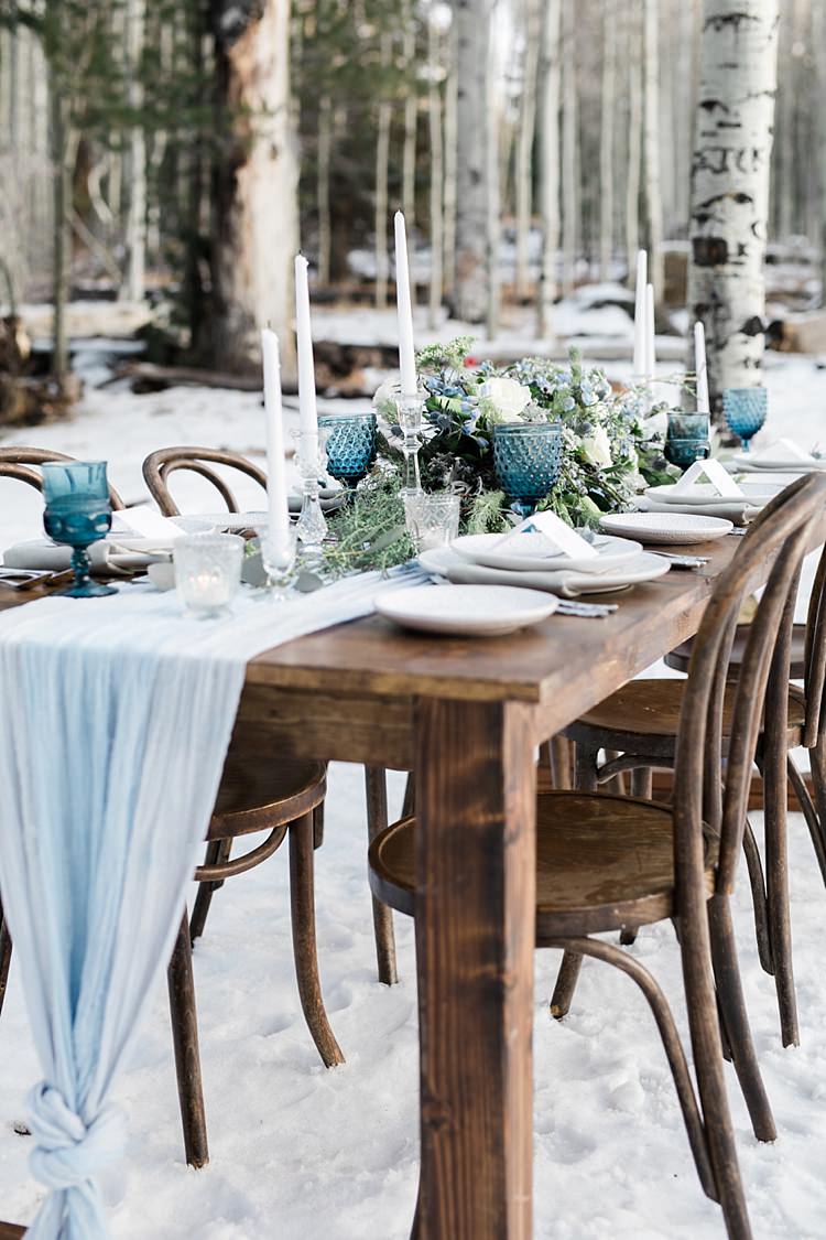 Outdoor Reception Wooden Table Blue Grey Fabric Fresh White Blue Green Flowers Blue Wine Goblets Glass Candlesticks Snowy Winter Wonderland Anniversary Shoot http://ryannlindseyphotography.com/