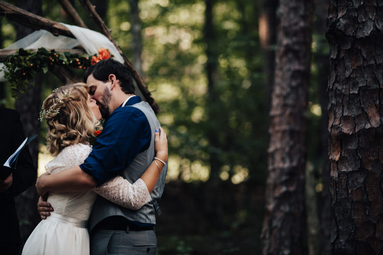 Outdoor Ceremony Bride Handmade Lace Bridal Gown Groom Grey Vest Pants Navy Blue Shirt Decorated Wooden Arbour Adventure Inspired Woodland Wedding North Carolina http://www.amandasuttonphotography.com/