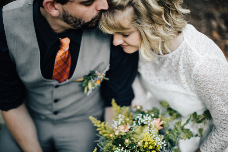 Outdoor Ceremony Location Bride Handmade Lace Bridal Gown Bouquet Orange Florals Gypsophila Groom Grey Vest Pants Navy Blue Shirt Orange Checkered Tie Buttonhole Orange Florals Succulent Adventure Inspired Woodland Wedding North Carolina http://www.amandasuttonphotography.com/