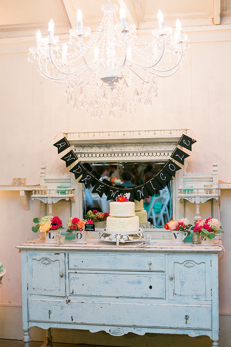 Reception Cake Table Vintage Dresser Large Chandelier Handwritten Bunting Wedding Cake Bright Multicoloured Florals Flower Farm Outdoor Wedding Minnesota http://eileenkphoto.com/