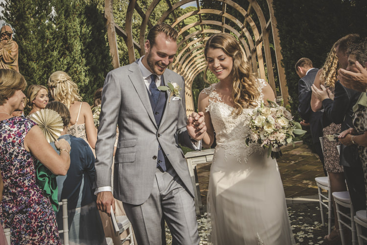 Outdoor Ceremony Bride Lace Tulle Stella York Bridal Gown Bouquet White Pink Roses Groom Light Blue Suit White Shirt Textured Blue Tie Guests Archway Green Hedges Romantic Intimate Tuscany Destination Wedding http://angelicabraccini.com/