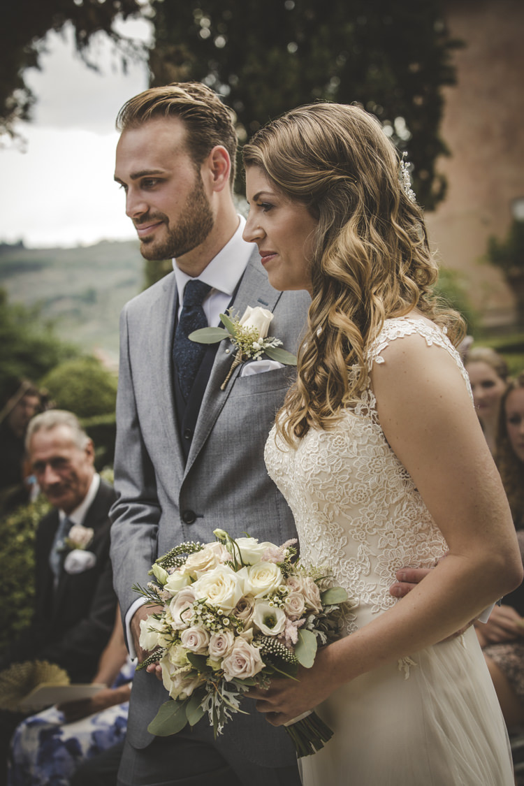 Outdoor Ceremony Bride Lace Tulle Stella York Bridal Gown Bouquet White Pink Roses Groom Light Blue Suit White Shirt Textured Blue Tie Rose Buttonhole Guests Romantic Intimate Tuscany Destination Wedding http://angelicabraccini.com/