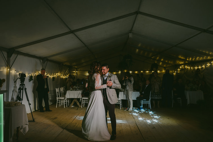 Reception White Marquee Bride Two Piece Lace Bridal Gown Groom Light Blue Shirt Sand Jacket Brown Pants Dancing Hanging Fairy Lights Natural Greenery Stylish Wedding Transylvania https://raresion.com/