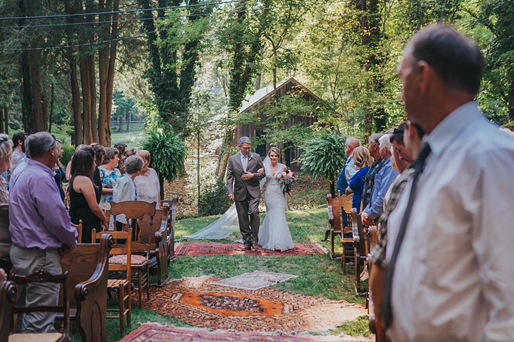 Outdoor Ceremony Bride V Neck Lace Embellished Bridal Gown Veil Multicoloured Bouquet Father Entrance Bright Rugs Guests Mismatched Wooden Chairs Bohemian & Whimsical Garden Wedding in North Carolina http://www.taylorparkerphotography.com/