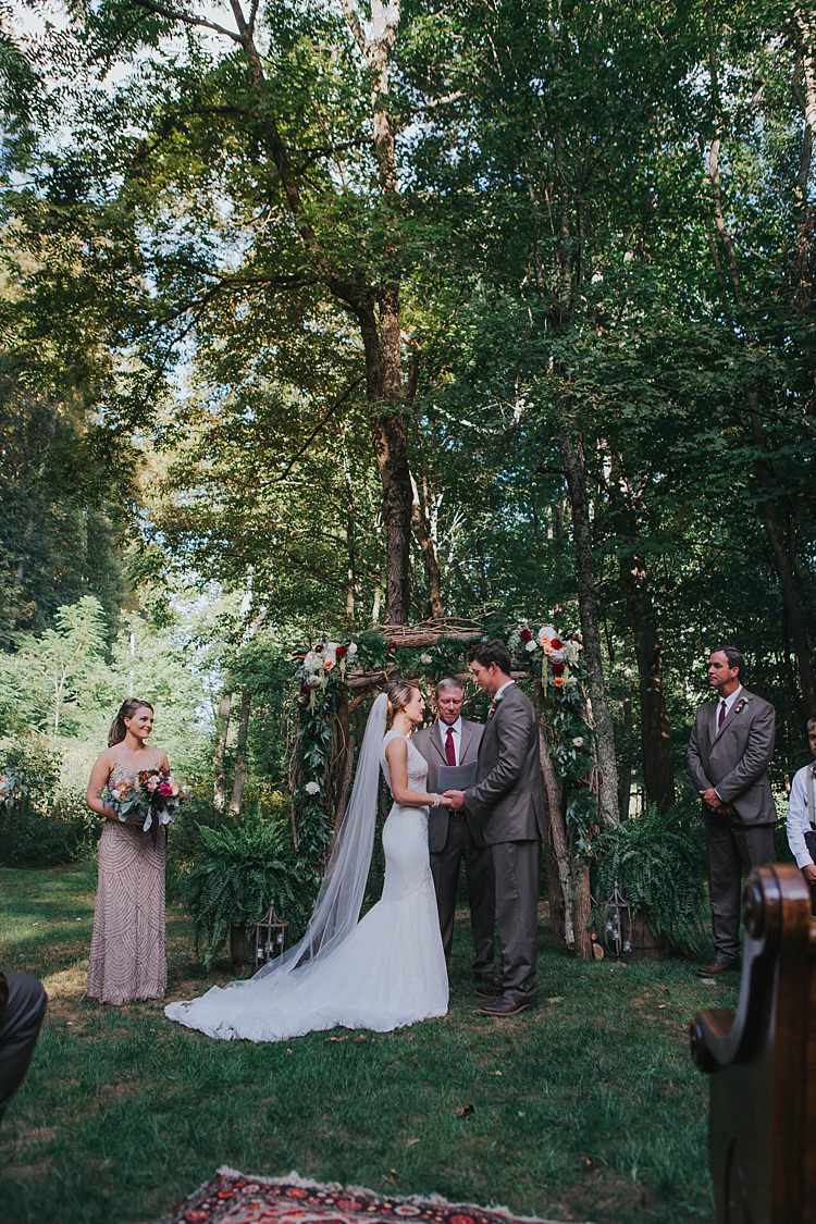 Outdoor Ceremony Floral Arch Bride Lace Embellished Gown Long Veil Groom Grey Suit White Shirt Celebrant Bridal Party Bohemian & Whimsical Garden Wedding in North Carolina http://www.taylorparkerphotography.com/