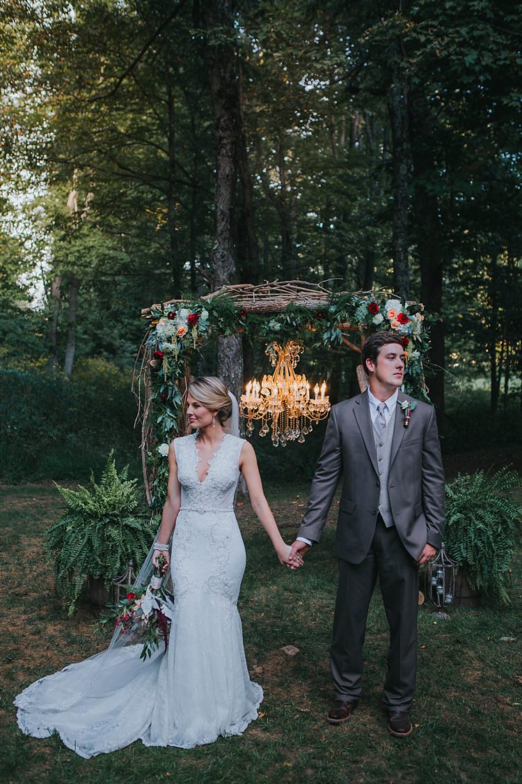 Outdoor Ceremony Wooden Floral Arch Multicoloured Flowers Greenery Chandelier Bride V Neck Lace Embellished Gown Long Veil Multicoloured Bouquet Groom Grey Suit White Shirt Light Grey Tie Vest Bohemian & Whimsical Garden Wedding in North Carolina http://www.taylorparkerphotography.com/
