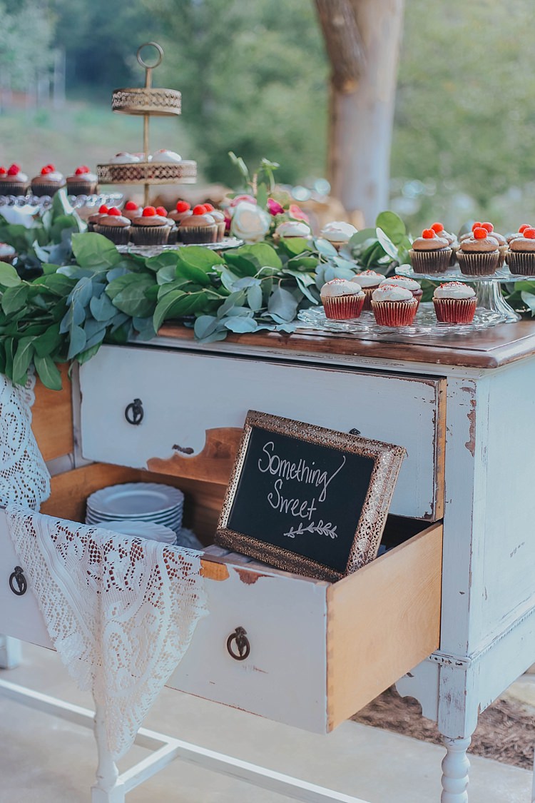 Reception Dessert Table White Antique Dresser Lace Tablecloth Blackboard Sign Gold Frame Cupcakes Gold Stand Greenery Bohemian & Whimsical Garden Wedding in North Carolina http://www.taylorparkerphotography.com/