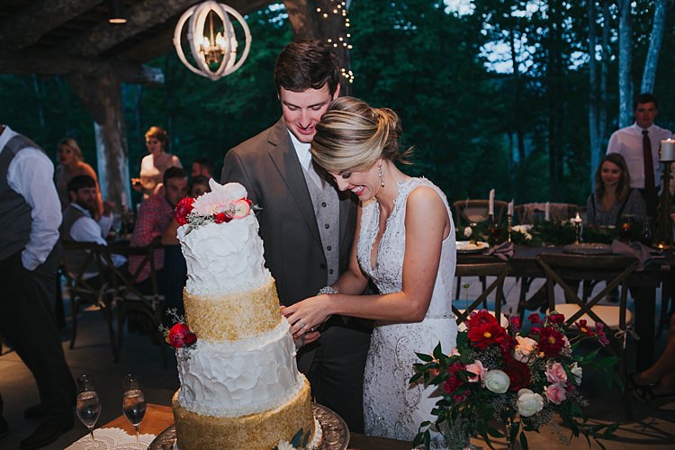 Reception Wedding Cake Cutting White Gold Sparkle Icing Multicoloured Florals Bride V Neck Lace Embellished Gown Groom Grey Suit White Shirt Light Grey Tie Vest Guests Bohemian & Whimsical Garden Wedding in North Carolina http://www.taylorparkerphotography.com/