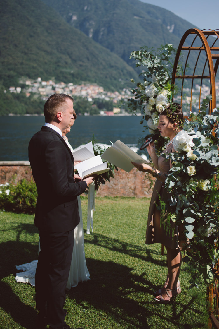 Outdoor Ceremony Bride V Neck Jenny Packham Bridal Gown Groom Tailored Black Suit White Shirt Celebrant Rusty Arch White Cream Florals Greenery Lake View Botanical Copper Greenery Lake Como Wedding http://margheritacalatiphotography.com/