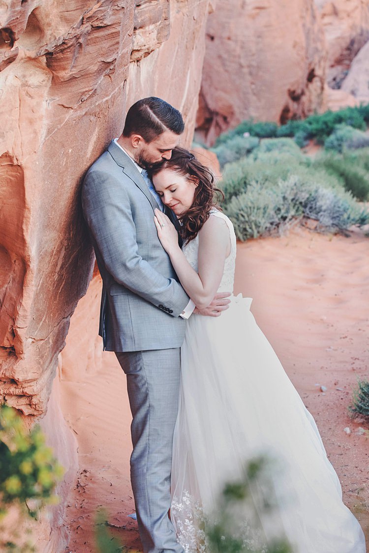 Bride Groom Embrace Windy Valley of Fire Wedding Nevada https://cactusandlaceweddings.com/