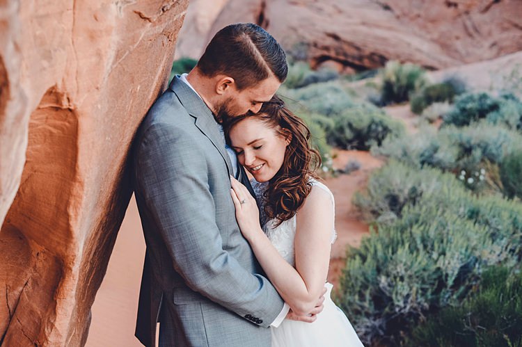 Bride Groom Embrace Windy Valley of Fire Wedding Nevada https://cactusandlaceweddings.com/