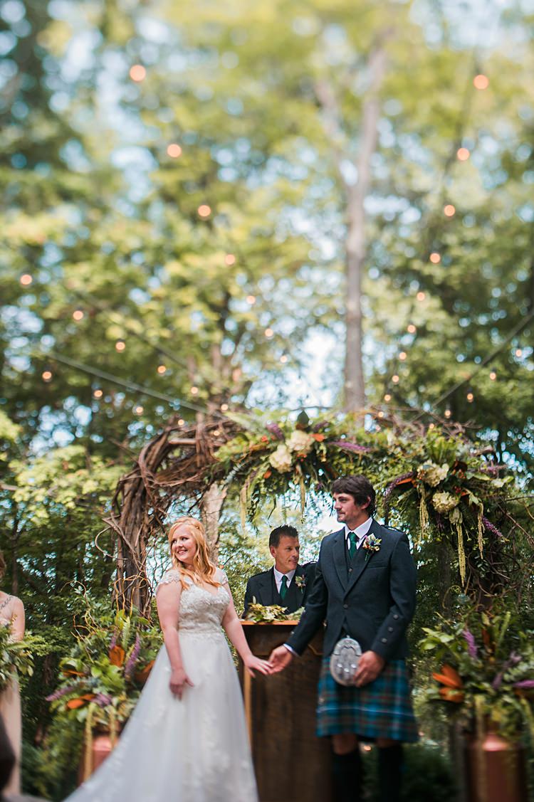 Bride Groom Ceremony Archway Tartan Kilt Greenery Thistle Outdoor Gown Lace Train Cap Sleeve Festoon Lighting Whimsical Woods Wedding Barn Ohio http://www.connectionphotoblog.com/