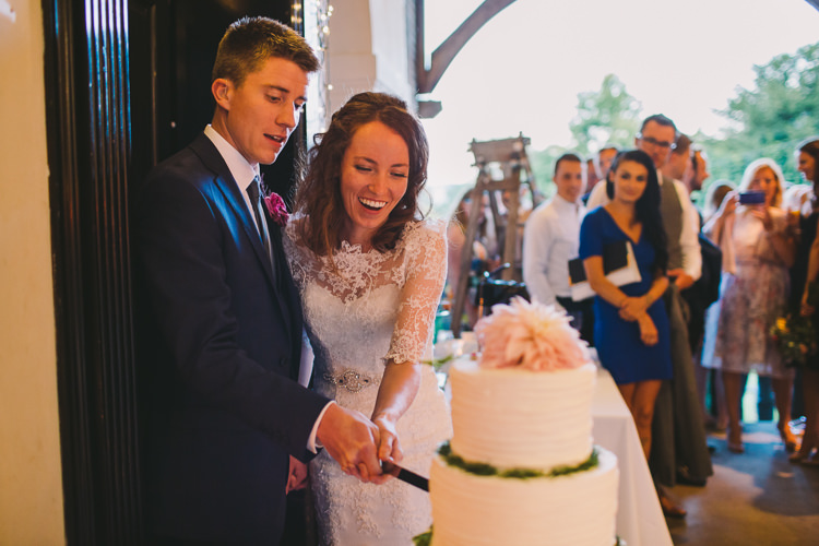 Bride Bridal Dress Gown Sweetheart Neckline Lace Jacket Diamante Belt Moss Bros Groom Navy Suit Three Piece Waistcoat Cake Cutting Buttercream Dahlia Fairy Lights Vibrant Florals Summer Barn Wedding https://www.oliviajudah.co.uk/