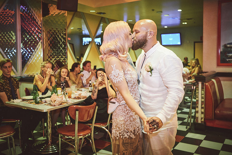 Bride Groom Kiss Wedding Reception Diner Pink Hair Sheer Gown Blush Lace Tattoos Hip Elvis Las Vegas Destination Wedding http://www.roseimages.co.uk/