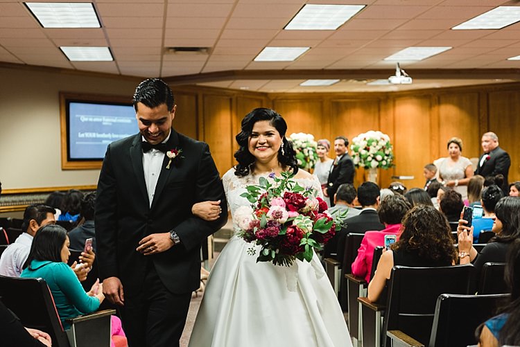 Bride Groom Aisle Recession Bowtie Lace Dress Off Shoulder Sleeves Bouquet Red Pink Peonies Roses Greenery Modern Romantic Winter Wedding Texas http://www.albarosephotography.com/