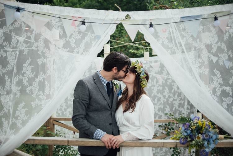 Bride Bridal Flower Crown Wildflower Bouquet Meadow long Sleeve Silk Dress 70s Grey Tweed Suit Navy Trousers Gingham Shirt Blue Lace Backdrop Festoon Lighting Bunting Adventurous Festival Bohemian Wedding https://libertypearlphotography.com/