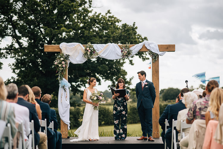 Wooden Arch Backdrop Ceremony Fabric Drapes Flowers Festival Bohemian Glamping Wedding https://theshannons.photography/