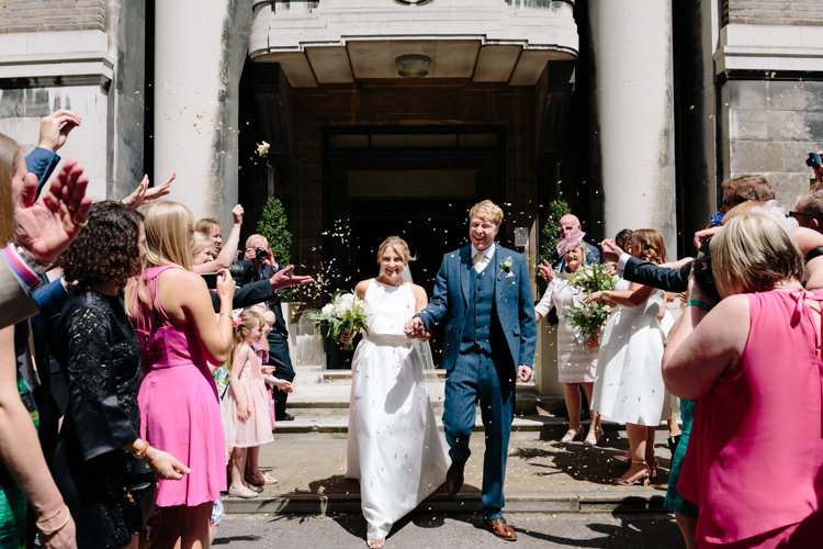 London Stoke Newington Town Hall Aisle Civil Ceremony Bride Groom Celebrate Confetti Shot | Modern Tropical Gold Urban Wedding https://www.christinewehrmeier.com/