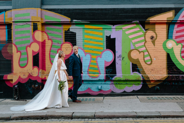 London City Bride Groom Buildings Graffiti Wall Street Foliage Greenery White Bouquet Jesus Peiro Dress Navy Suit | Modern Tropical Gold Urban Wedding https://www.christinewehrmeier.com/