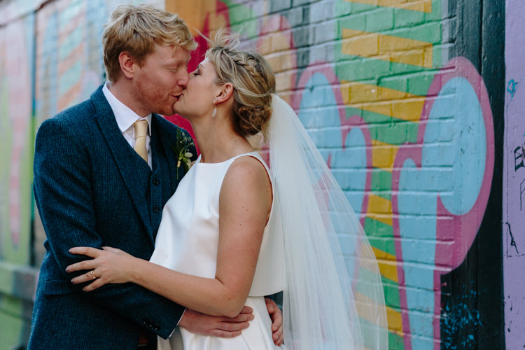 London City Bride Groom Buildings Street Graffiti Wall Kiss Jesus Peiro Dress Navy Suit | Modern Tropical Gold Urban Wedding https://www.christinewehrmeier.com/