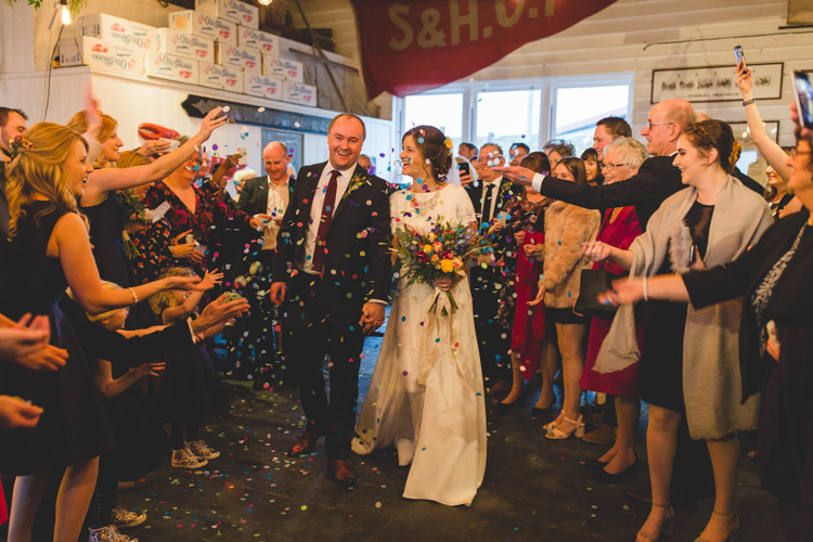 Confetti Shot Groom Navy Suit Bride Bridal Floor Length T Shirt Neckline Short Sleeves Multicolour Wild Flower Bouquet Colourful Fun Cosy Rainy Sea Wedding http://www.livvy-hukins.co.uk/