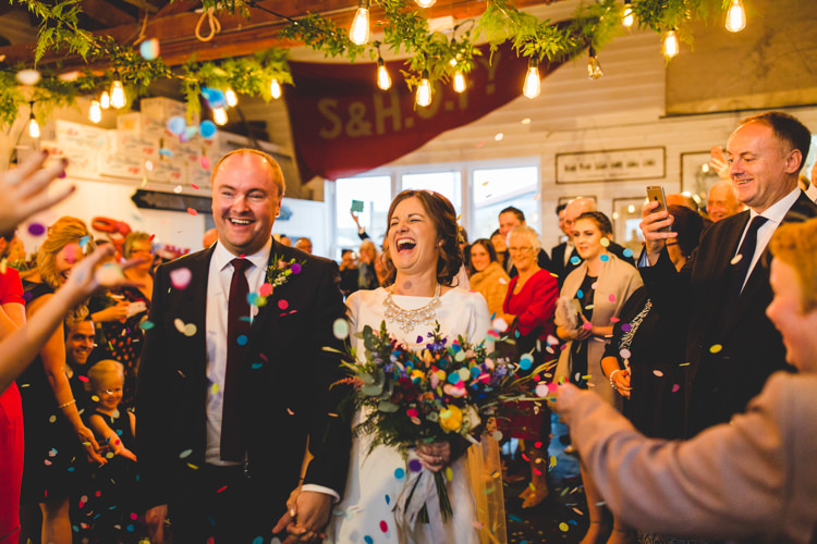 Groom Navy Suit Bride Bridal Floor Length T Shirt Neckline Short Sleeves Multicolour Wild Flower Bouquet Confetti Shot Colourful Fun Cosy Rainy Sea Wedding http://www.livvy-hukins.co.uk/